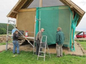 Nachdem die zweite Lehmputz aufgetragen worden ist, wird gleichzeitig die Fl&auml;che mit einem Wetterschutznetz abgedeckt.