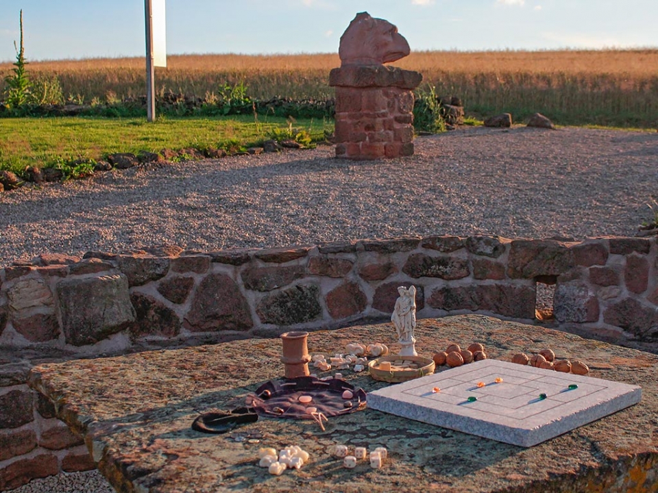 Eine Auswahl r&ouml;mischer Spiele auf dem Sandsteintisch an der Exedra - nat&uuml;rlich mit dem strengen Blick des Greifenkopfes